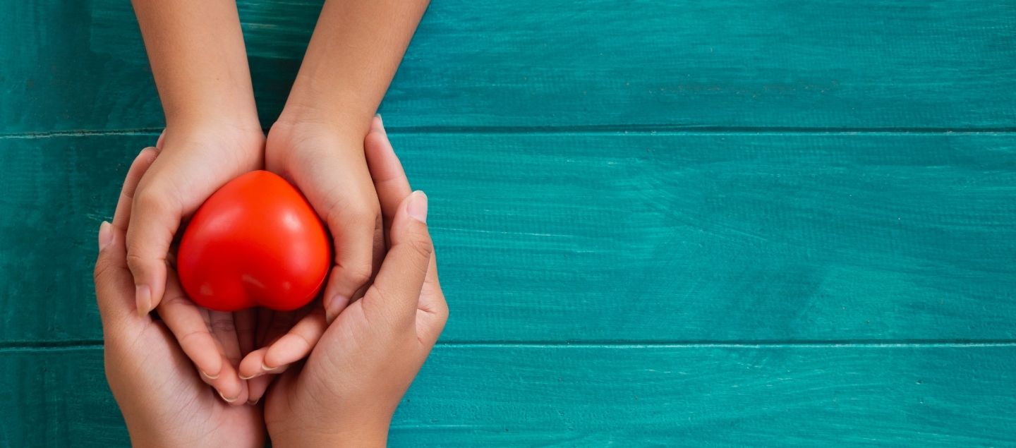 Two pairs of hands holding a heart